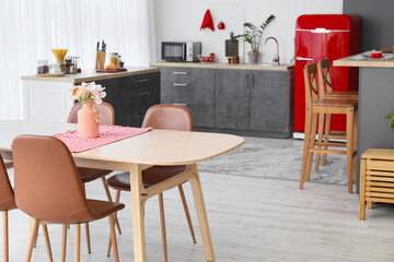 Interior of modern kitchen with red fridge, counters and dining table