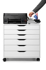 Businessman taking pen from holder on chest of drawers with modern printer against white background