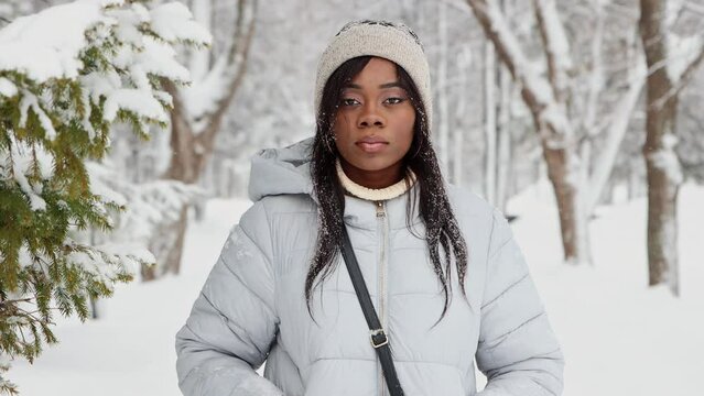 Young black woman in white jacket walks in winter forest