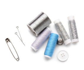 Thread spools with button, pin and needles on white background