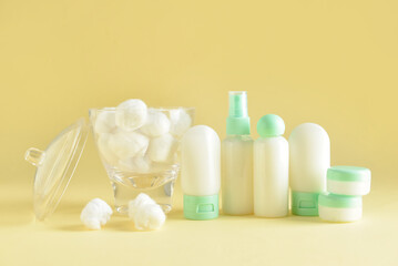 Travel bottles, jars with cosmetic products and cotton balls on beige background