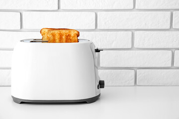 Modern toaster with bread slices on light table