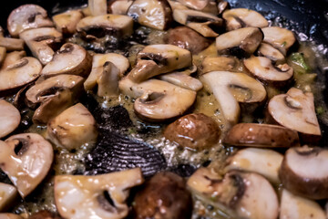Macro, selective focus on baby bella mushrooms cooking in a large, nonstick skillet