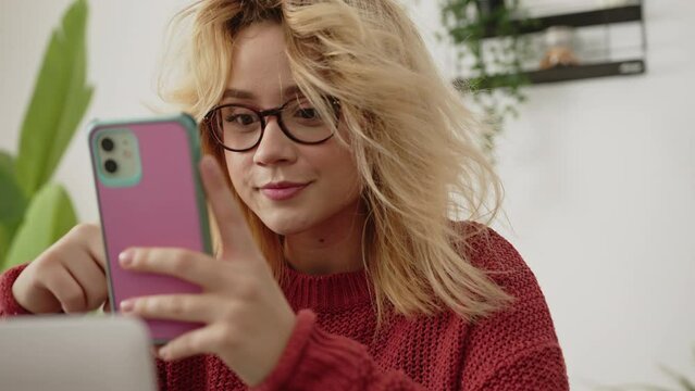 Blonde young Millenial girl on her cell phone. Social media. remote Work. Mobile