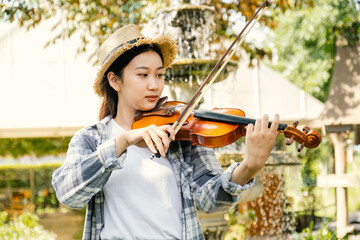Close-up portrait of Young Asia woman music violinist play violin, relax in the garden with peace of mind