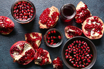 Jars and bowl of pomegranate molasses with fresh fruits on black background