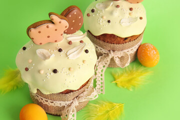 Delicious Easter cakes decorated with cookies, feathers and painted eggs on green background