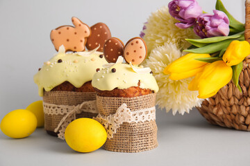 Fototapeta na wymiar Delicious Easter cakes decorated with cookies, flowers and painted eggs on light background