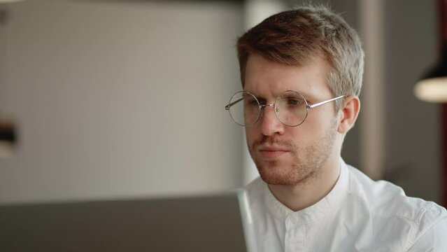 office worker is looking at screen of laptop and thinking, reading information and sending email