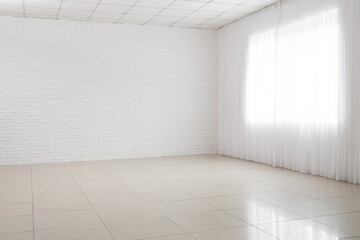 View of big empty room with white brick wall and window