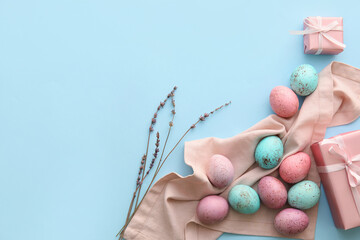 Painted Easter eggs, willow branches and gift boxes on blue background