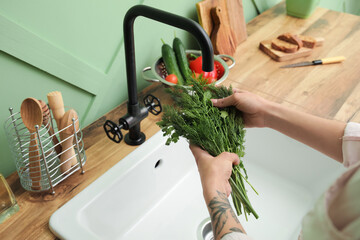 Obraz na płótnie Canvas Woman washing greenery over ceramic sink in kitchen, closeup