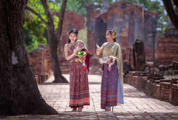 Naklejka premium Beautiful Asian woman wearing Thai dress traditional pose happiness to playing splash water during Songkran festival is funny festival traditional holiday in Thailand .