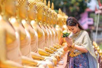 Thai woman in an ancient Thai dress holds a garland of fresh flowers paying homage to Buddha to...