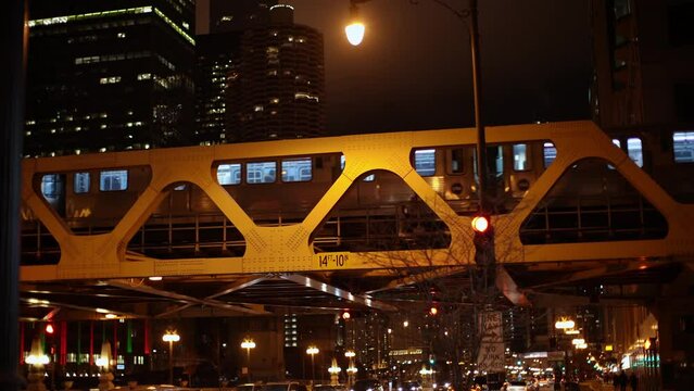 CTA Train passing over River on Elevated Track at Night. Train cars illuminated inside. Subway in Chicago