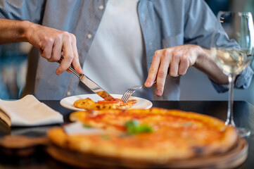Close up picture of a ma cutting pizza