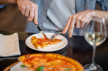 Close up picture of a ma cutting pizza