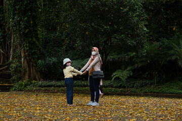 photo of mother and daughter holding hands against tree background