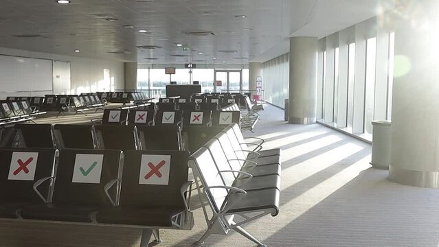 Airport during the Covid-19 pandemic. Empty departure hall and seats with special social distancing signs