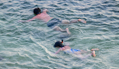 Father and daughter snorkeling together in Galle beach, view from a high angle.