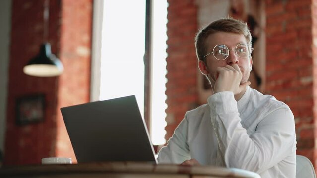 freelance journalist or translator is working with laptop in cozy cafe in daytime, handsome man in white shirt