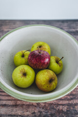 group of green apples with one red apple in the middle, healthy food or metaphor of standing out from the crowd