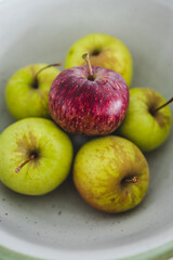 group of green apples with one red apple in the middle, healthy food or metaphor of standing out from the crowd