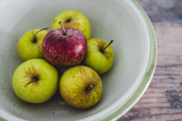 group of green apples with one red apple in the middle, healthy food or metaphor of standing out from the crowd