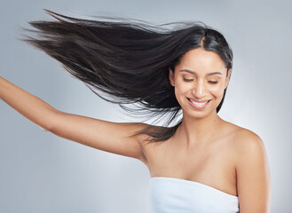 My hair sure is perfect. Shot of an attractive young woman standing alone in the studio and flipping her hair.
