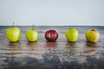 group of green apples with one red apple in the middle, healthy food or metaphor of standing out from the crowd