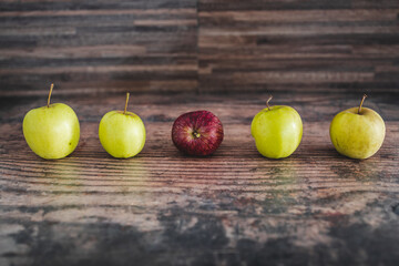group of green apples with one red apple in the middle, healthy food or metaphor of standing out from the crowd
