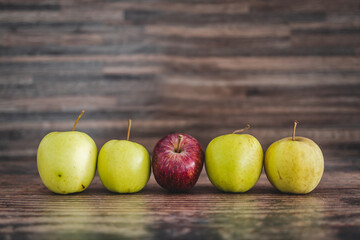 group of green apples with one red apple in the middle, healthy food or metaphor of standing out from the crowd
