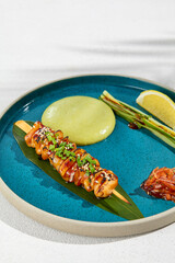 Squid yakitori in ceramic dish on white background. Japanese skewered squid with wasabi sauce. Grilled kalmar on bamboo skewer in asian style. Food menu for izakaya. Summer pan asian menu. © Ryzhkov