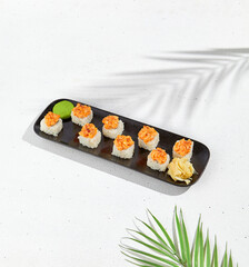 Maki sushi with salmon top on black plate. Sushi roll with philadelphia cheese inside and salmon tartare outside. Maki roll in minimal concept. Summer menu for japanese restaurant.