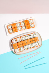 Set of salmon sushi rolls. Philadelphia maki in ceramic dishware on coloured backdrop. Sushi menu concept. Modern japanesse food. Maki sushi with salmon in minimal style