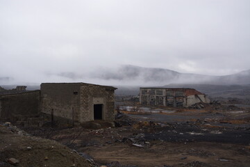 Destroyed houses and buildings. Nature pollution. Old abandoned huge coal pit. Ruins and stones. Ruins and huge mountains of dirty rock. Concrete industrial building. Dust and damaged house