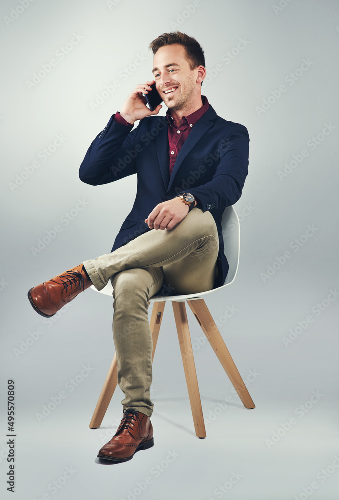 Poster the man to call to make it happen. studio shot of a confident young businessman using a mobile phone