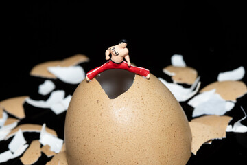 A mini figure of a martial arts expert stretching his legs on an egg shell.