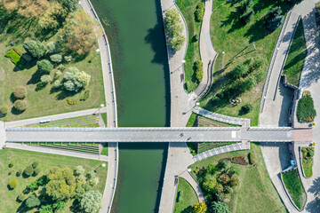 Fototapeta premium walking bridge in the summer park across the river. aerial top view.