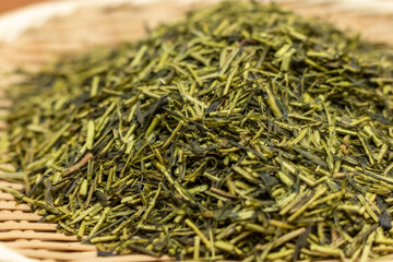 竹ザルの上の緑色のお茶の葉にクローズアップ