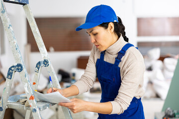 Woman foreman in overalls signs an act of acceptance of completed work