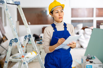 Woman foreman checks the completed construction work on the drawing