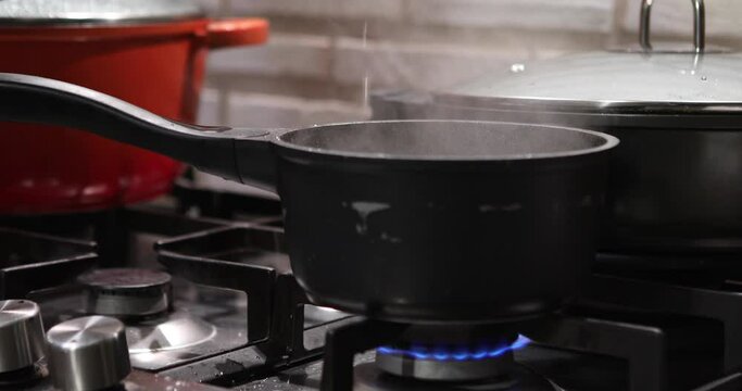 Saucepan with lid on the fire of gas stove removes the lid and steam comes out