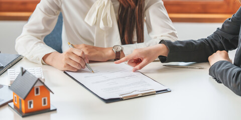 Close up of Business woman pointing and signing agreement for buying house. Bank manager concept.