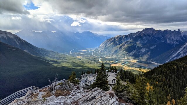 A view from the very top of Sulphur Mountain in Alberta. On this cloudy day, the sun peaks through to shine a beam of light into the valley between several mountain ridges.