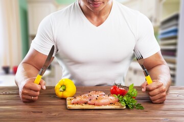 attractive handsome male eating health food salad and chicken at home. Active young man sit on table, healthy foods and clean water for breakfast to diet for health care