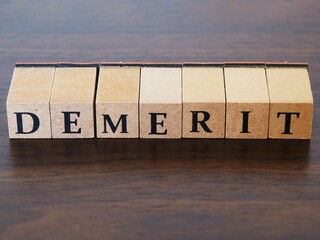 デメリット(demerit)と書かれた木のブロックのタグ