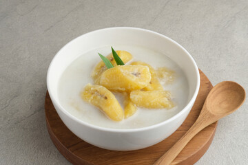 Kolak, Kolak Pisang is Indonesian traditional dessert, very popular during Ramadhan, made from banana with coconut milk, sugar and pandanus leaves. Served in white bowl on grey background, copy space.
