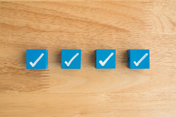 Check mark sign on blue block checklist wooden background copy space. Checklist and questionnaire in business, education concept.