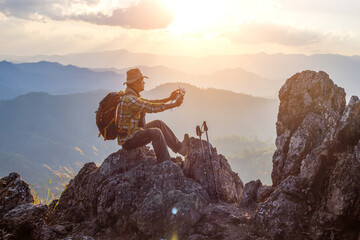 hiker with backpack checks map to find directions in wilderness area on top mountain sunset...